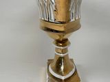 a silver vase on a gold stand on a white background