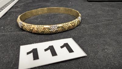 un bracelet en or posé sur une table noire, sur lequel figure le chiffre 11