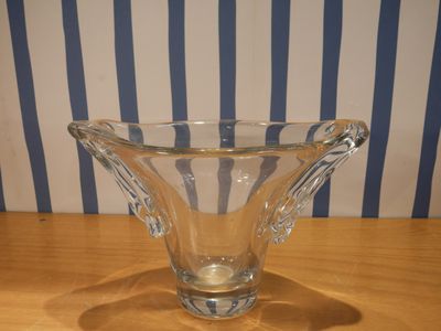 a glass vase sitting on a table with a striped wall behind it