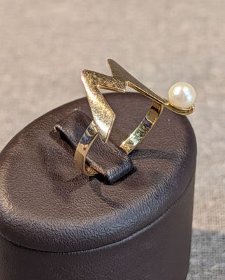 une bague sertie d'une perle, posée sur une boîte