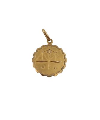 a close up of a gold pendant on a white background