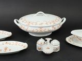 five pieces of white and orange china on a black table