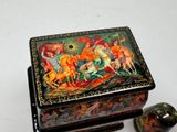 a small box with a painting on it next to a small object