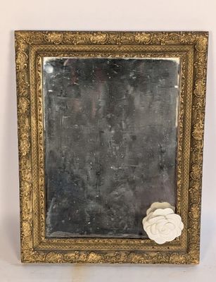 un miroir à cadre doré orné d'une rose blanche