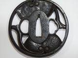 une tsuba en fer noir comportant une inscription sur un fond blanc