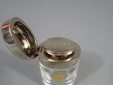 a small glass jar with a silver lid on a table