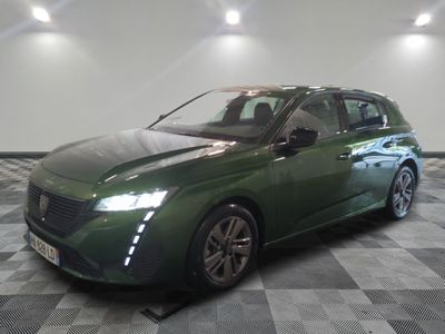 La voiture verte est garée sur un sol à damier dans le garage.