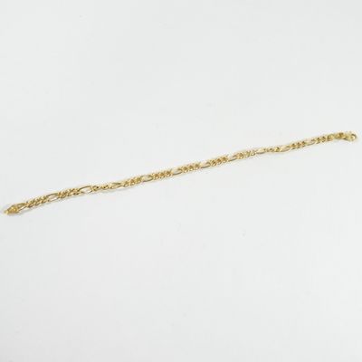 gros plan d'un bracelet en chaîne en or sur une surface blanche