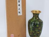 un vase vert posé à côté d'une boîte sur une surface blanche