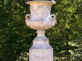 a white vase sitting on a pedestal in the middle of a field