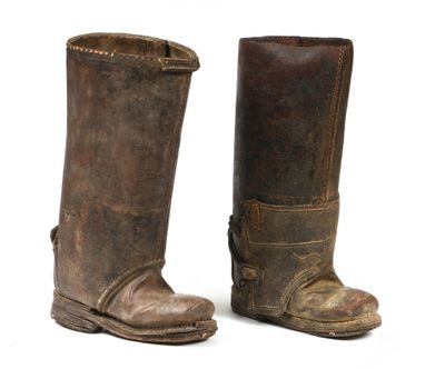une paire de vieilles bottes en cuir posées sur une surface blanche, avec un fond blanc