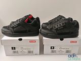 two boxes of black shoes sitting on top of each other on a white surface