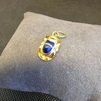 pendentif en or et lapis-lazuli, orné d'une pierre bleue posée sur un coussin