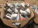 many pairs of shoes in a cardboard box on the ground