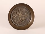 an antique bronze plate with an image of a man riding a horse