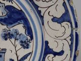 a blue and white plate with a picture of a man in a boat