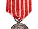 un gros plan d'une médaille sur fond blanc, ornée d'une bande rouge et blanche