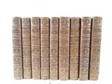several old books are lined up in a row on a white surface