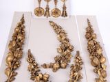 three pieces of gold jewelry are displayed on a white surface