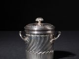 an old silver pot with a lid on a black surface