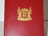 un livre rouge orné d'un blason doré