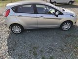 a small silver car parked in a gravel lot