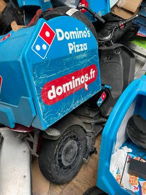 un tas de bric-à-brac surmonté d'un camion de livraison de pizzas Domino's bleu et rouge