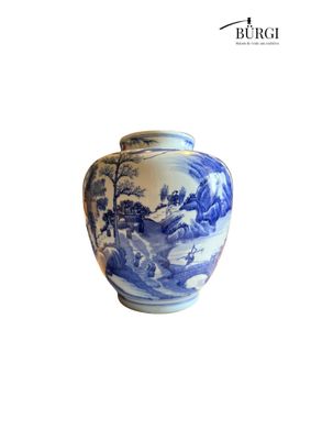 a blue and white vase sitting on a white surface