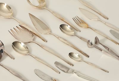 un grand nombre de cuillères et de fourchettes disposées sur la table