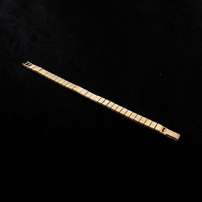 an image of a gold bracelet with a long bar on a black background