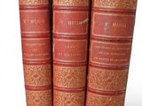 three old books are stacked on top of each other on a white surface