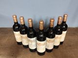 six bottles of wine are lined up on a wooden table