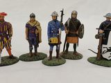 four figurines of men dressed in medieval clothing with shields and shields