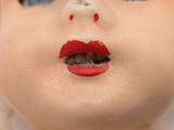 a close up of a doll ' s face with red lipstick on it