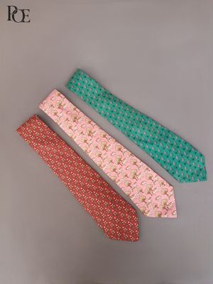 trois cravates de couleurs différentes posées sur une surface blanche, sur fond noir