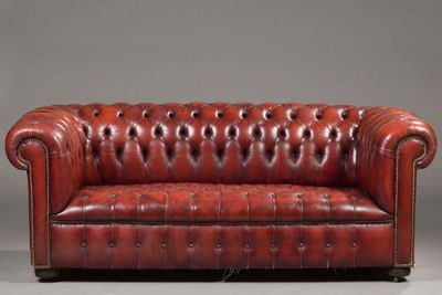 a red leather chesterfield sofa on a grey background