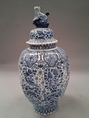 a blue and white vase with a bird on top of it