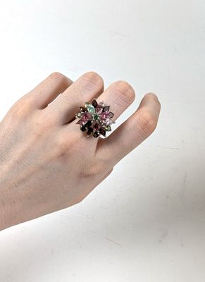 la main d'une femme tenant une bague ornée d'une fleur