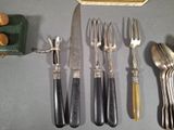 five forks, a knife, and a spoon on a table