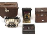 plusieurs types d'appareils photo anciens et de boîtes posés sur une surface blanche