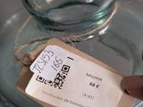 a person holding a tag in front of a glass jar