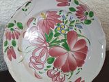 two plates with flowers painted on them sitting on a table