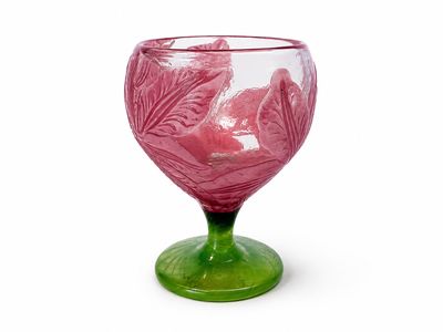 un gobelet en verre violet et vert posé sur un socle vert