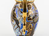 a blue vase with a gold handle on a white background