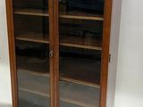 an old wooden cabinet with glass doors and shelves in a room