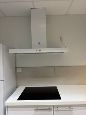 une cuisine blanche avec une plaque de cuisson noire et des placards blancs