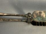 a silver comb with a metal handle on a white surface