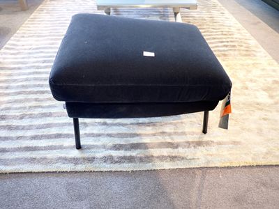 un pouf noir posé sur un tapis dans une pièce