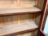 a wooden cabinet with a glass door and shelves