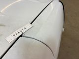 the front end of a white car with a measuring tape on it ' s hood